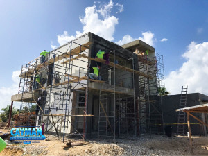 Five crew members apply concrete on scaffolding.