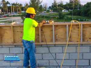A construction worker sands extended rebar on wood frame work.